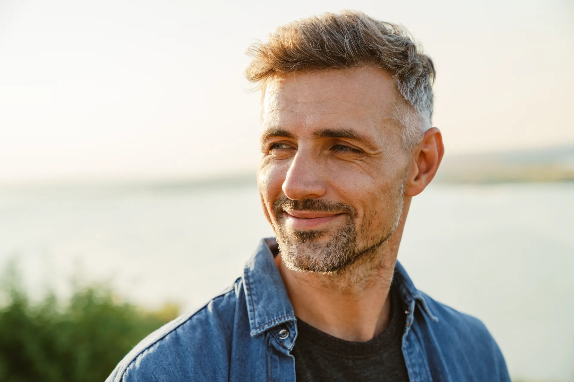 grey man smiling and looking aside while standing utc